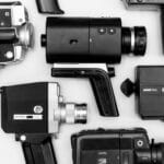 Flat lay of assorted vintage video cameras in black and white photography.