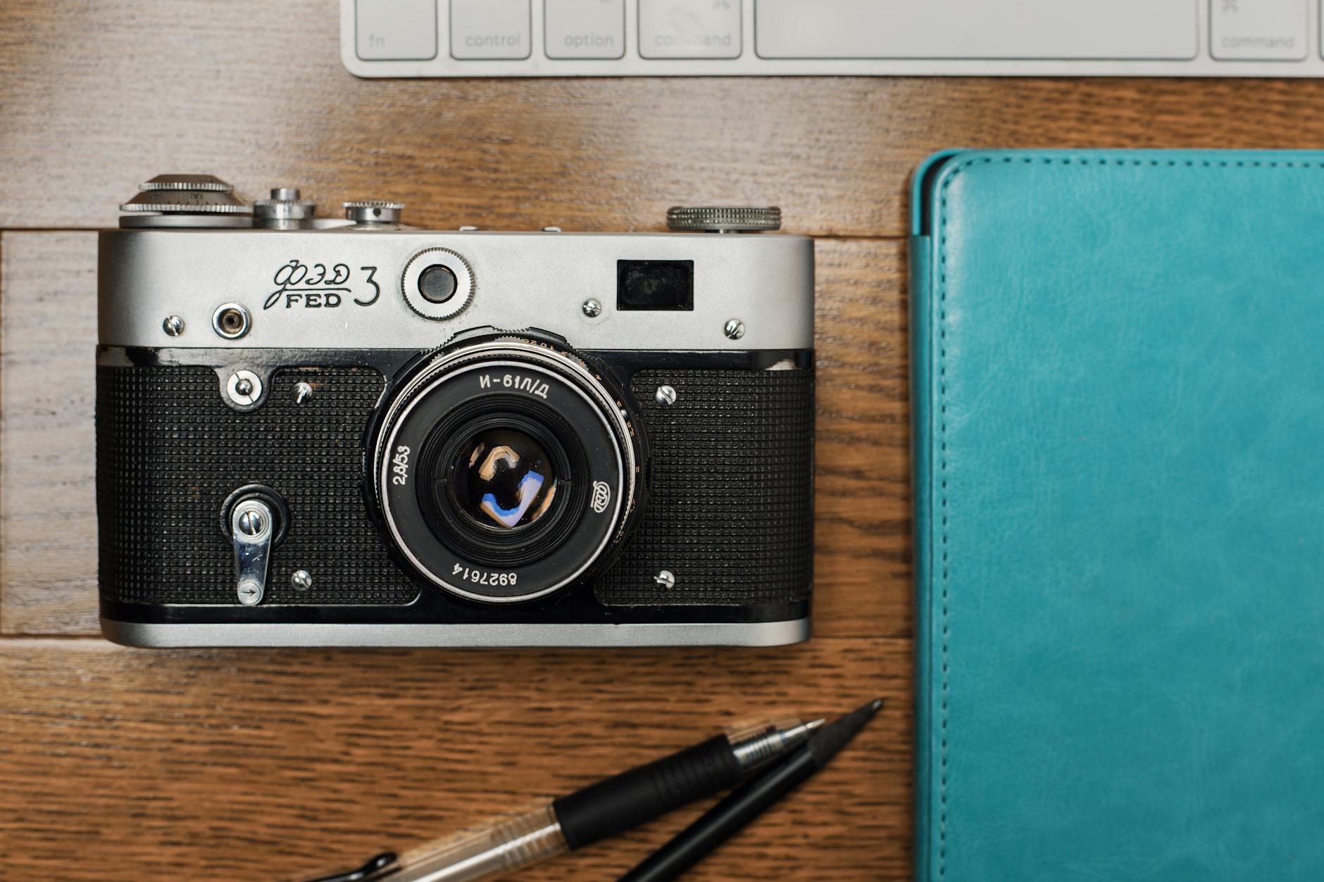 3 Million Photos Deleted: Eye-Opening Facial Recognition AI 12 facial recognition - A classic FED 3 film camera placed on a wooden desk with a blue notebook and pens.