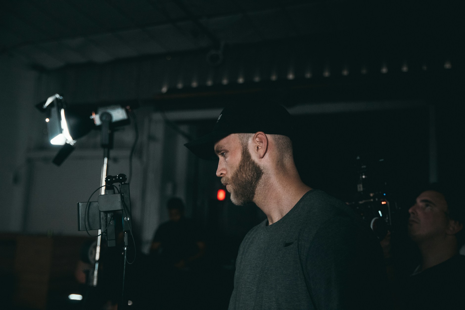 A cinematographer working behind a professional video camera in a low-lit studio.