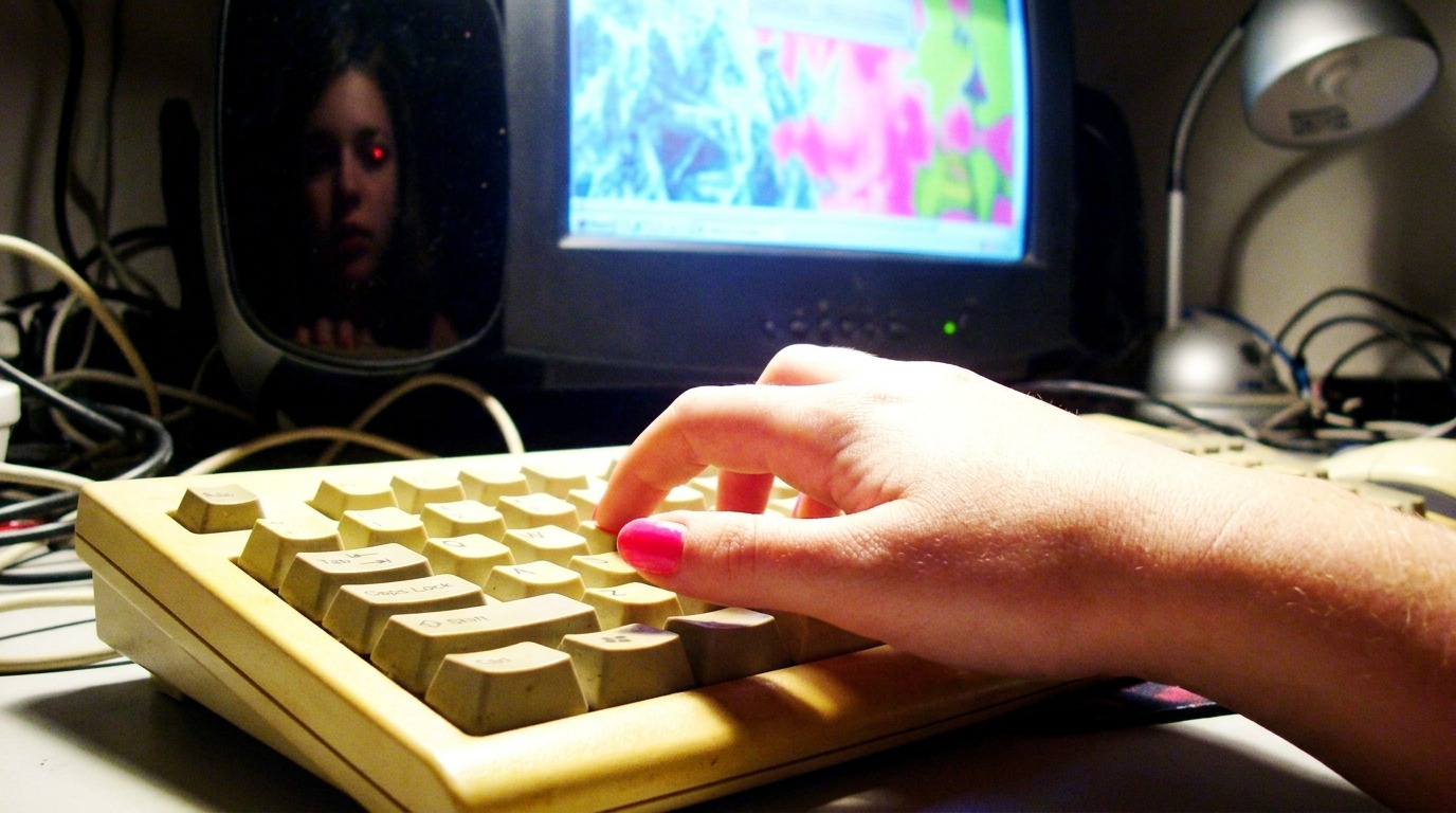 A persons fingers hover over an old, clunky keyboard from, y2k prompts