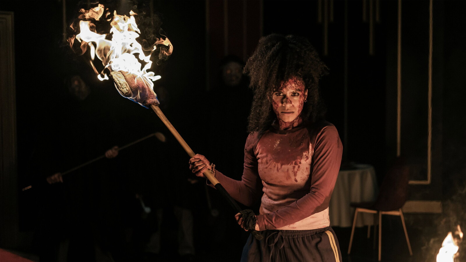 Asia carries a burning torch through the dark in They Will Kill You